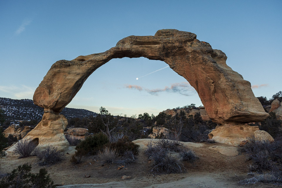 Anasazi Arch in the morning light with a full moon in the archway.